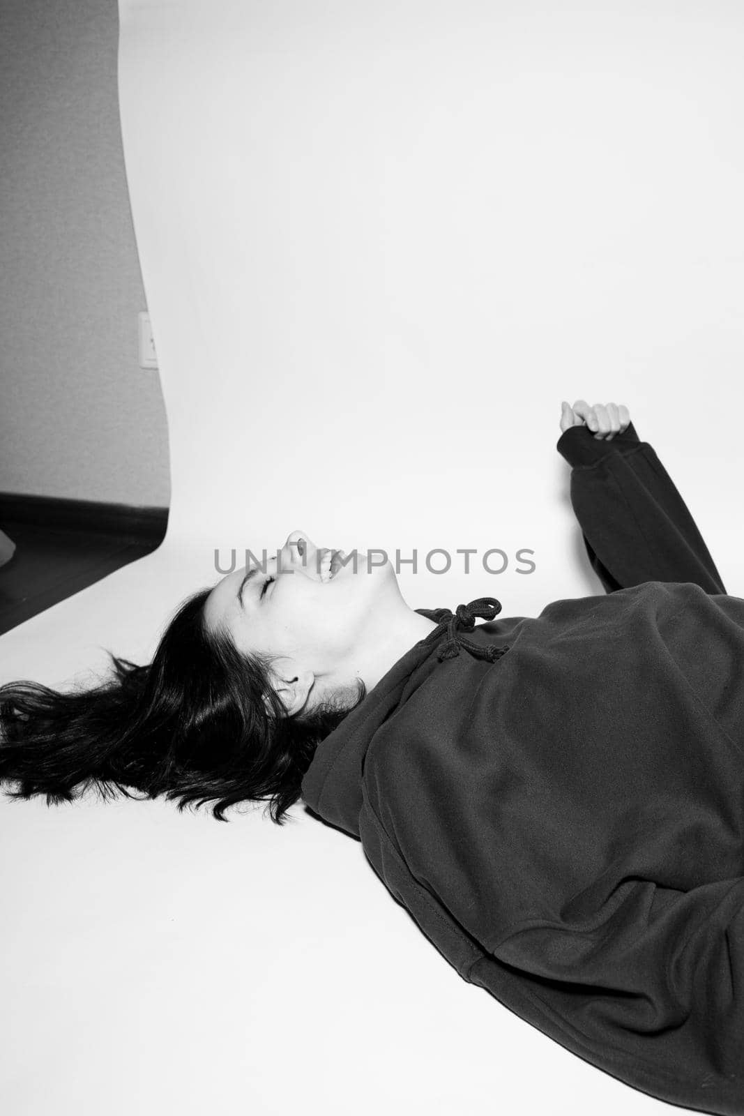 a woman in a black hoodie lies on the floor, black and white photography. High quality photo