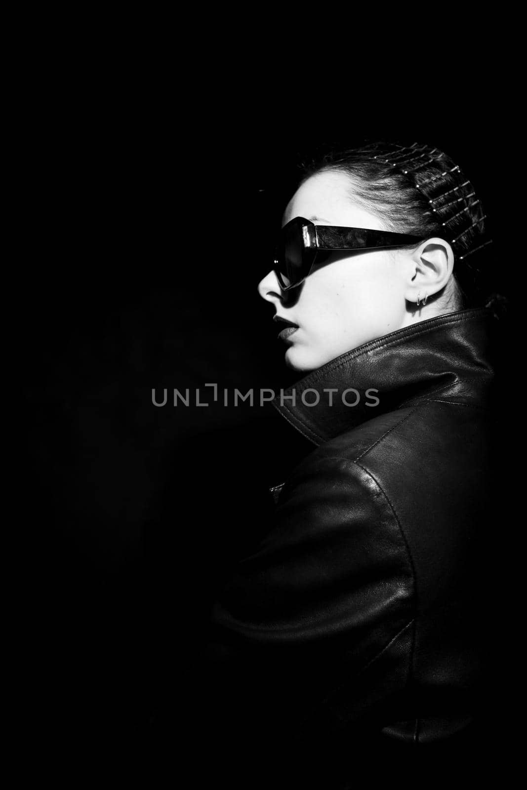 woman in leather coat and sunglasses, black background. High quality photo