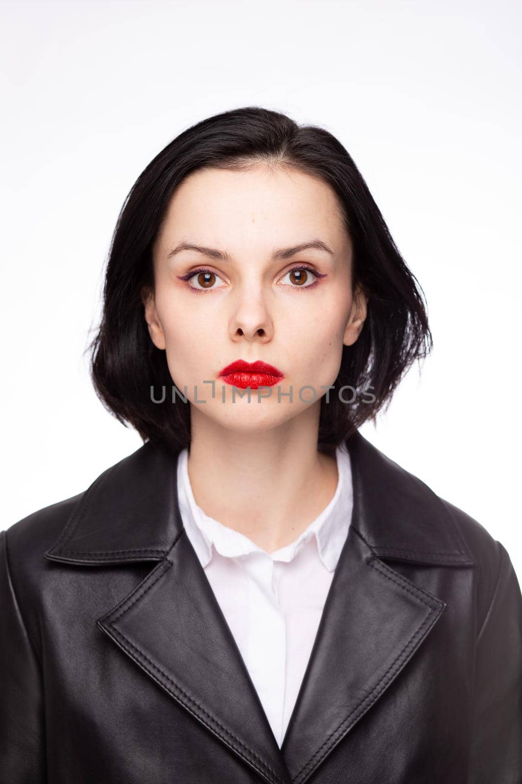 brunette woman with red lipstick on her lips in a black leather jacket and white shirt, white background by shilovskaya