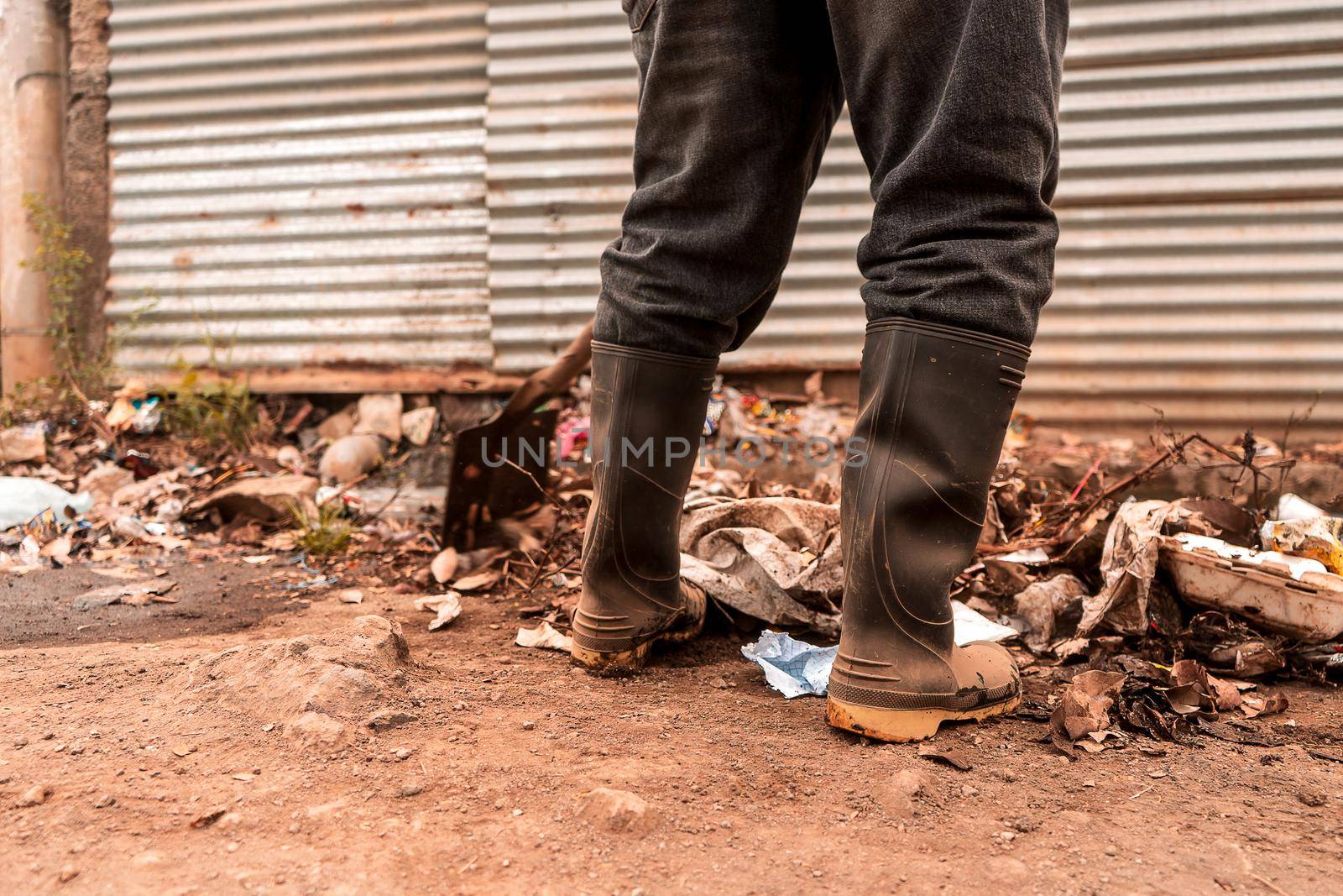 Closeup to the boots of a municipal worker collecting garbage in a poor neighborhood in Managua