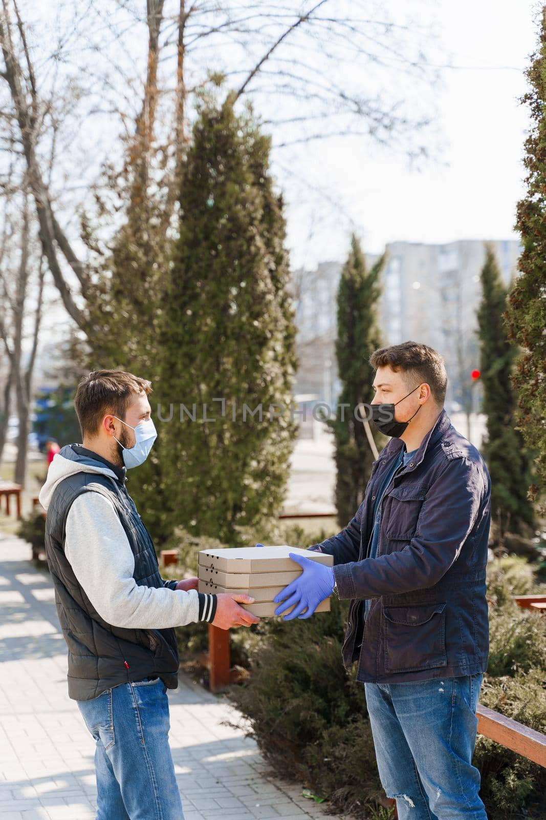 Courier in medical gloves gives 4 pizza boxes to customer who sick coronavirus covid 19. Safety food delivery form pizza restaurant