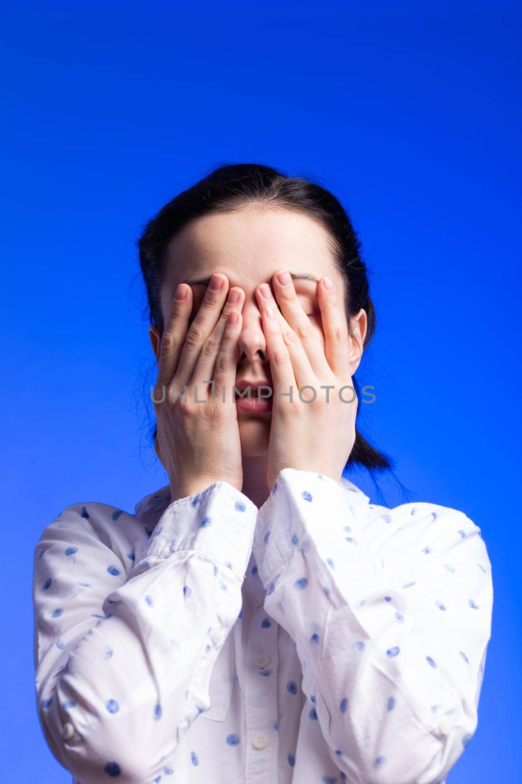 brunette woman in a white shirt with polka dots, on a blue background. High quality photo