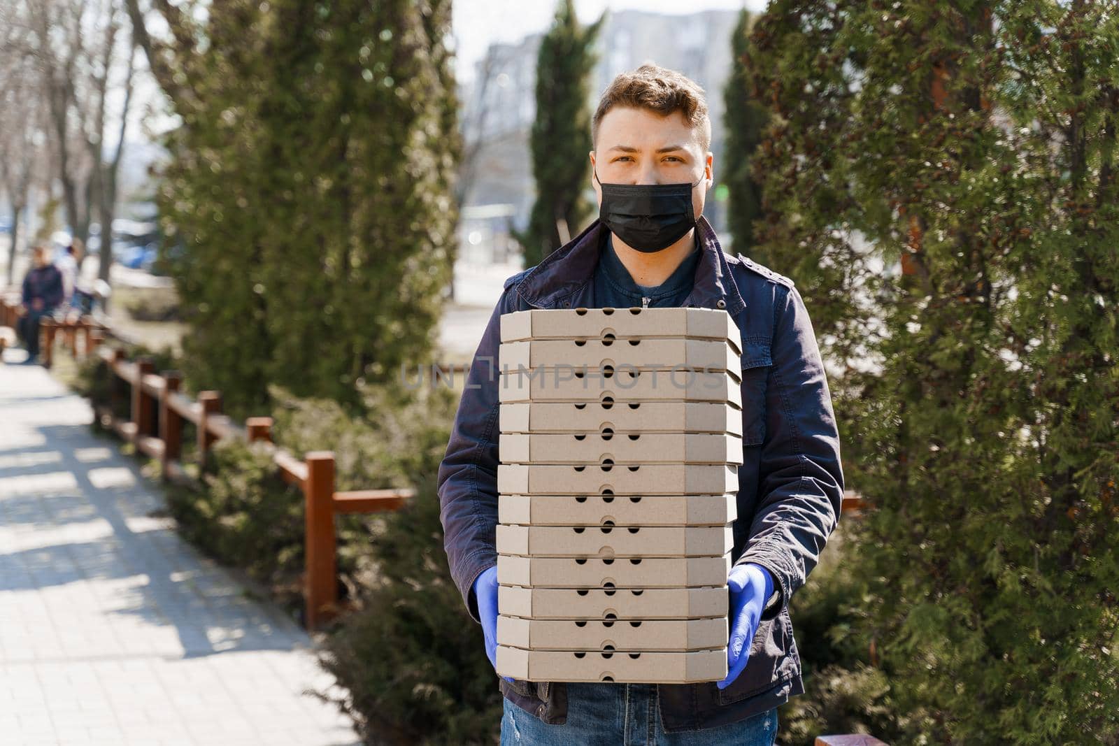 Young student works for food delivery. Courier with many boxes with pizza from restaurant. Stay at home on quarantine. Coronavirus covid 19