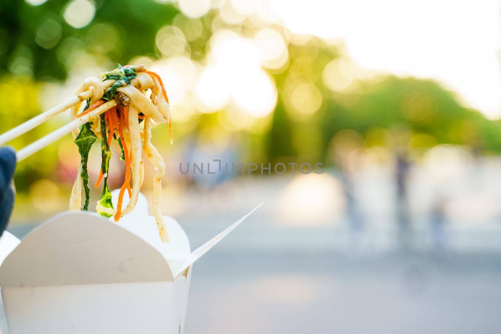 Closeup udon noddles on blurred background gets out of the white box. Stay at home and eat udon noodles with tempuru, shrimps, soy sauce. Safe delivery