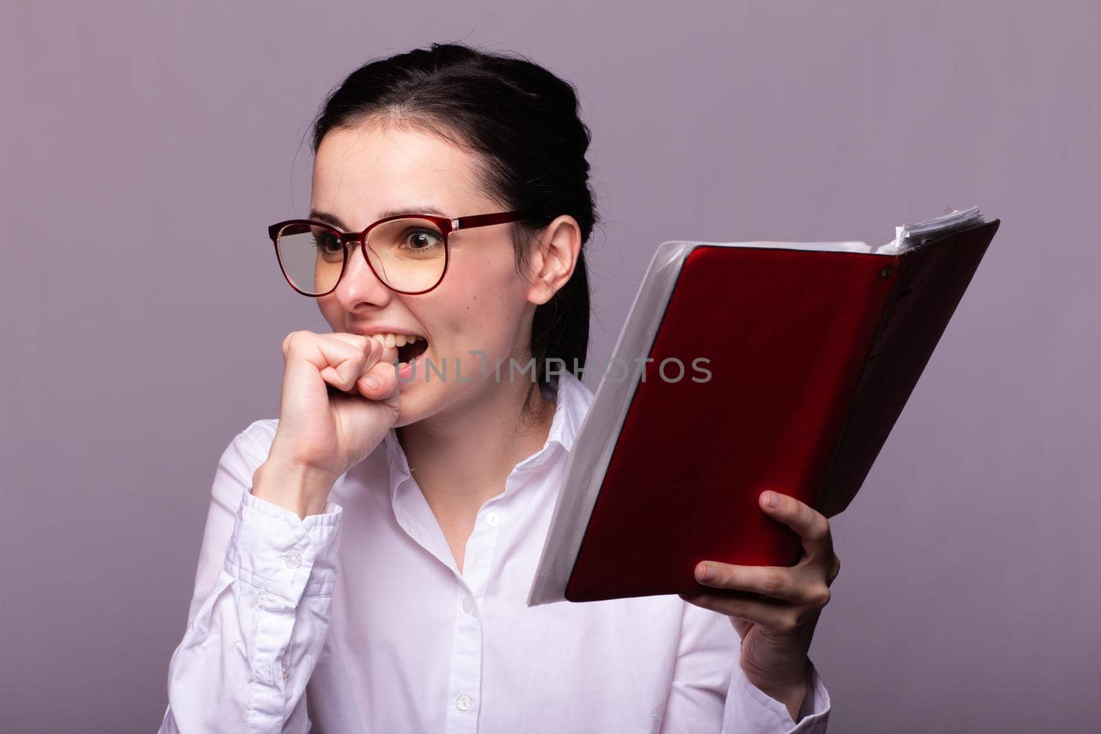 woman in a white shirt and glasses holds a red notebook in her hand. High quality photo