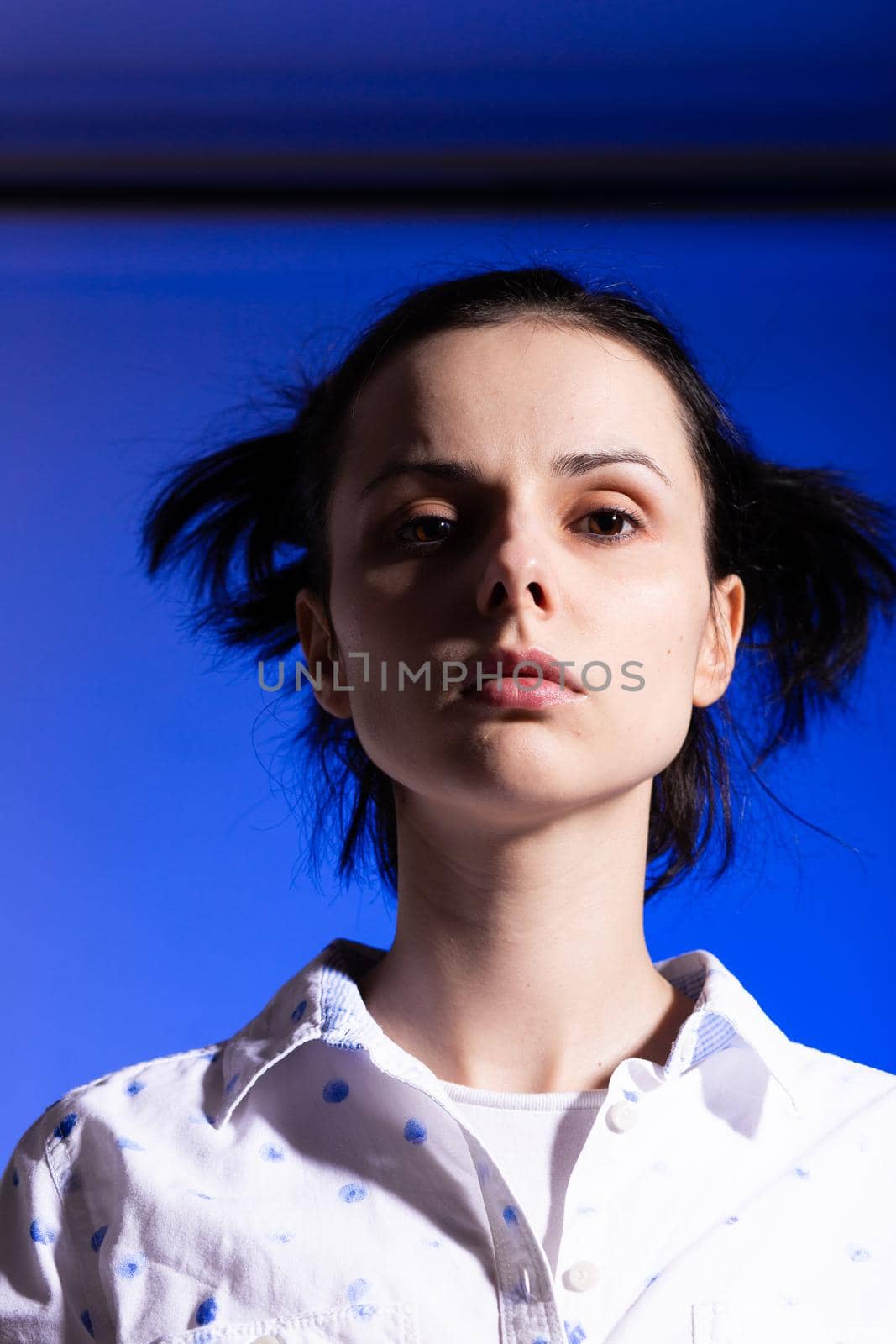 brunette woman in a white shirt with polka dots, on a blue background by shilovskaya