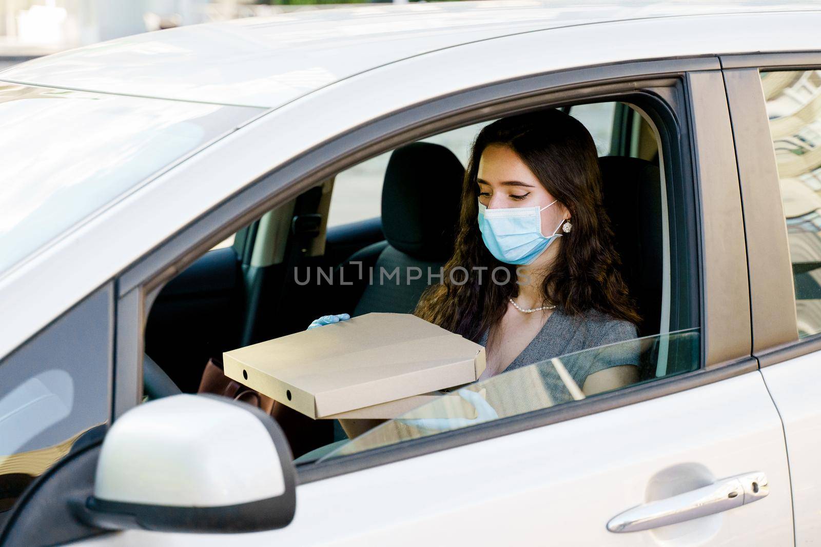 Lovely caucasian girl with green eyes looks at pizza and wants to eat. Courier in medical mask and gloves by Rabizo