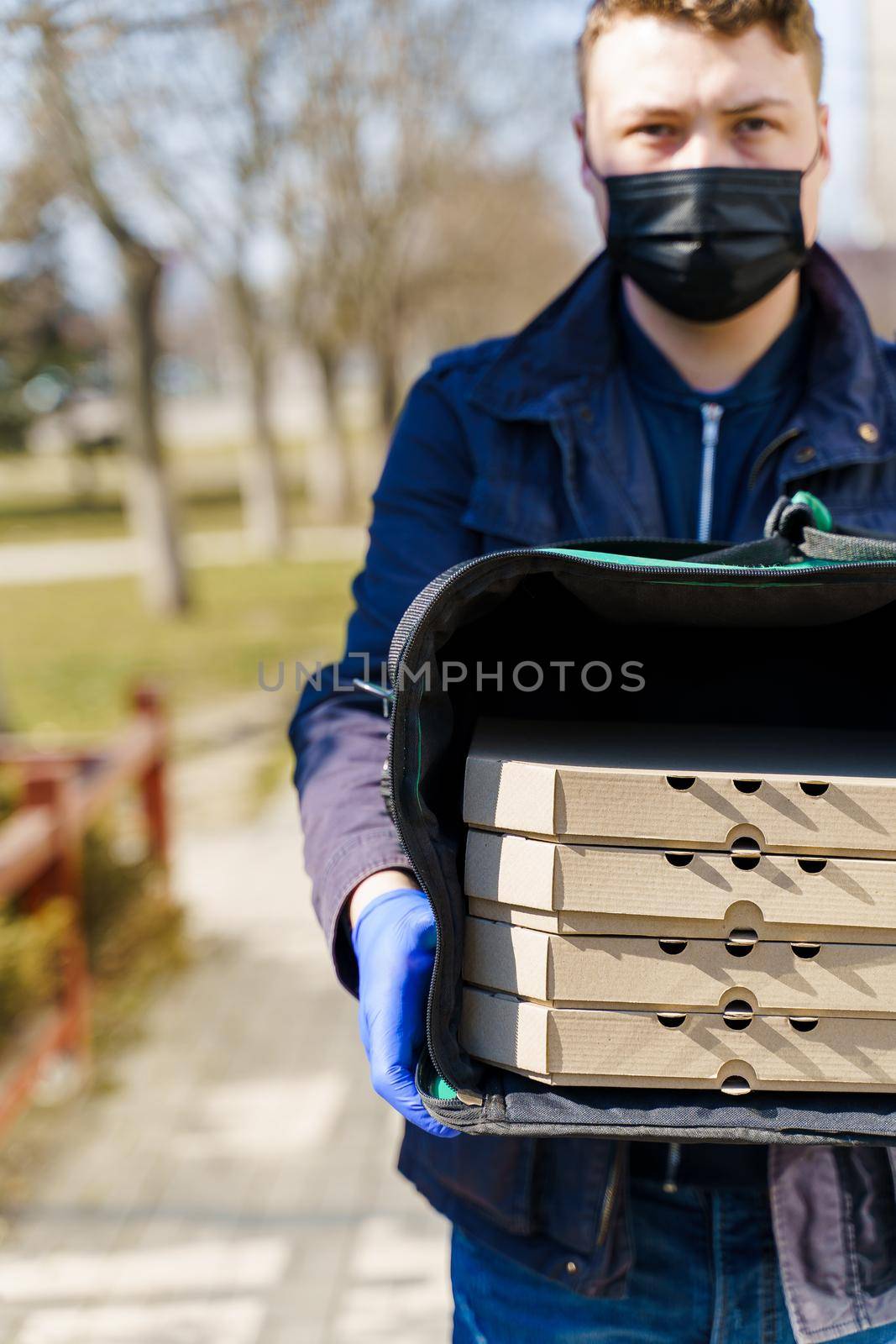 Safety food delivery in thermobag. 4 boxes of pizza. Courier in medical gloves for stop coronavirus covid 19. 2+2 pizza promotion.