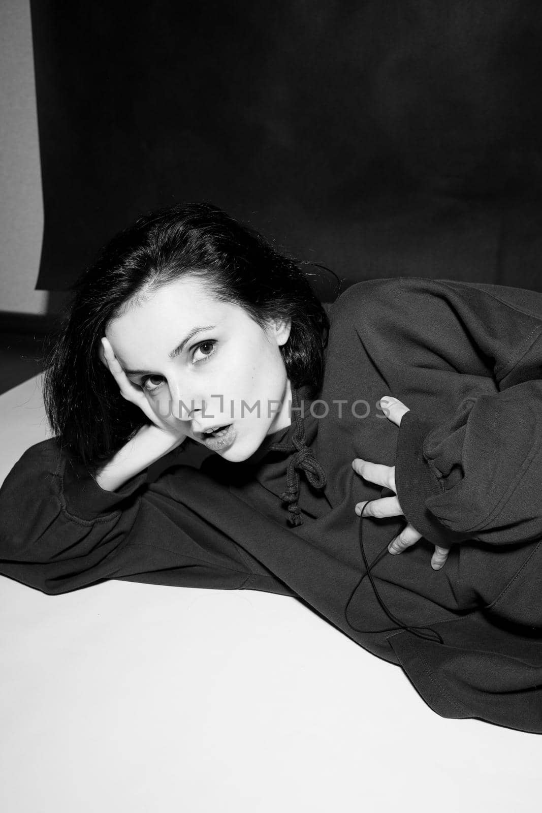 a woman in a black hoodie lies on the floor, black and white photography by shilovskaya