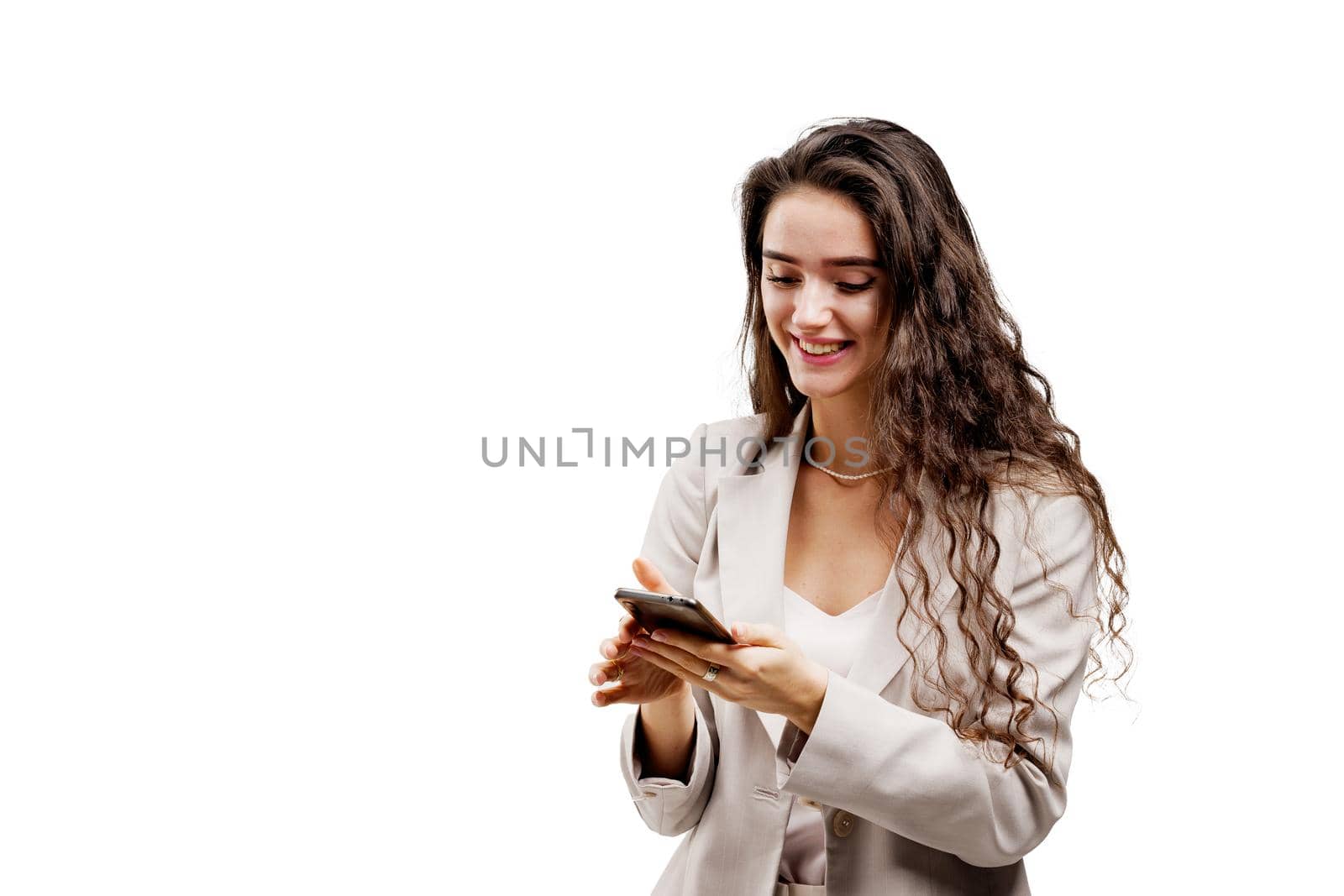 Girl is serfing on the internet using smartphone. Manager works on-line by phone. Attractive girl with curly hair holds phone in hands.