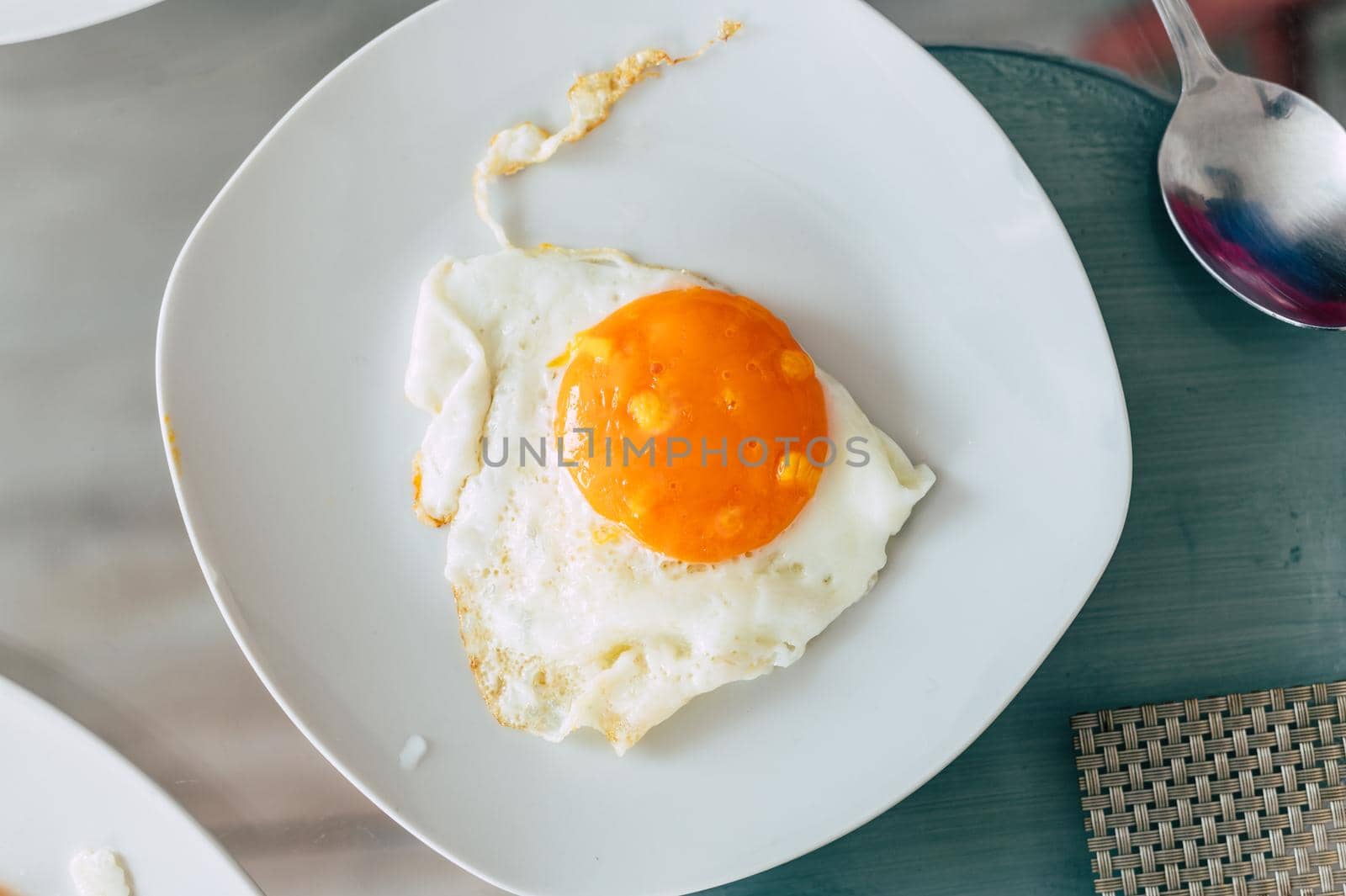 Top view of white plate with fried egg on glass table background. by Peruphotoart