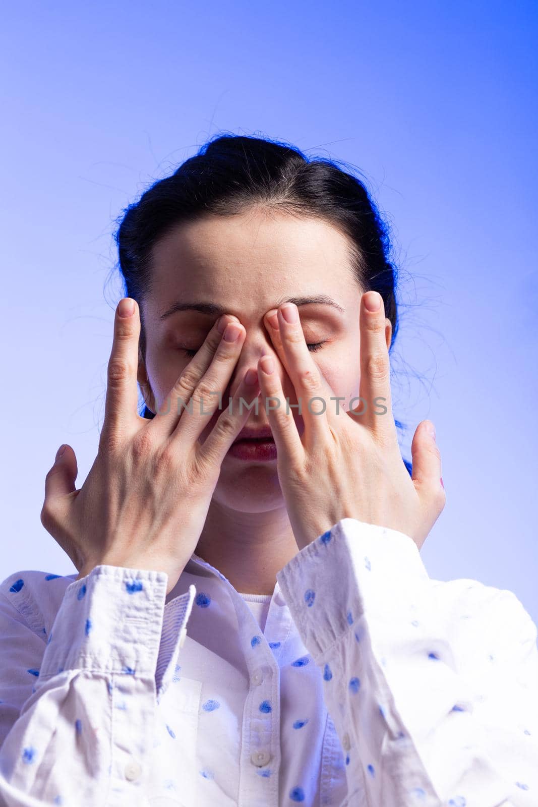 brunette woman in a white shirt with polka dots, on a blue background. High quality photo