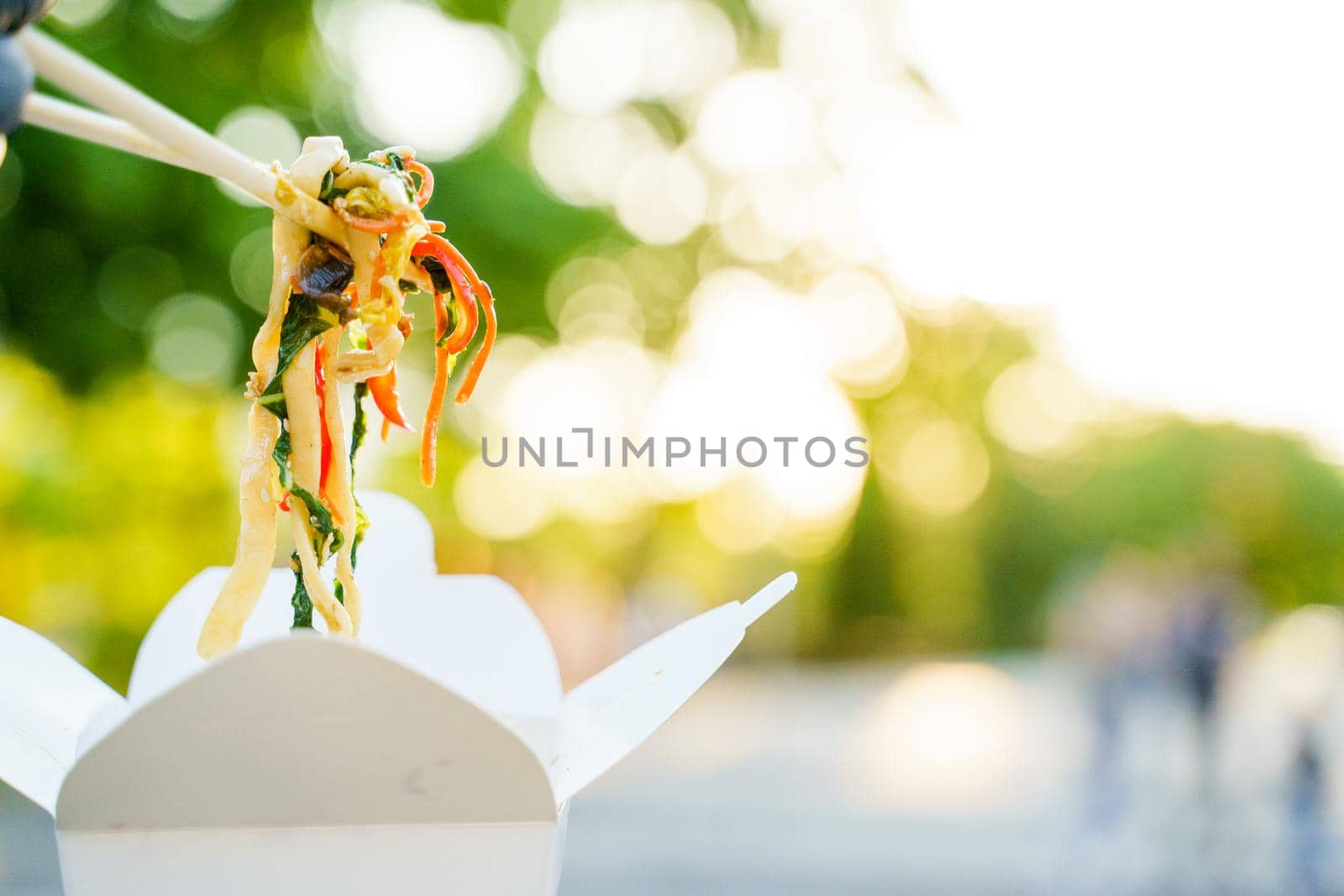 Close-up udon noddles on blurred background gets out of the white box. Stay at home and eat udon noodles with tempuru, shrimps, soy sauce by Rabizo