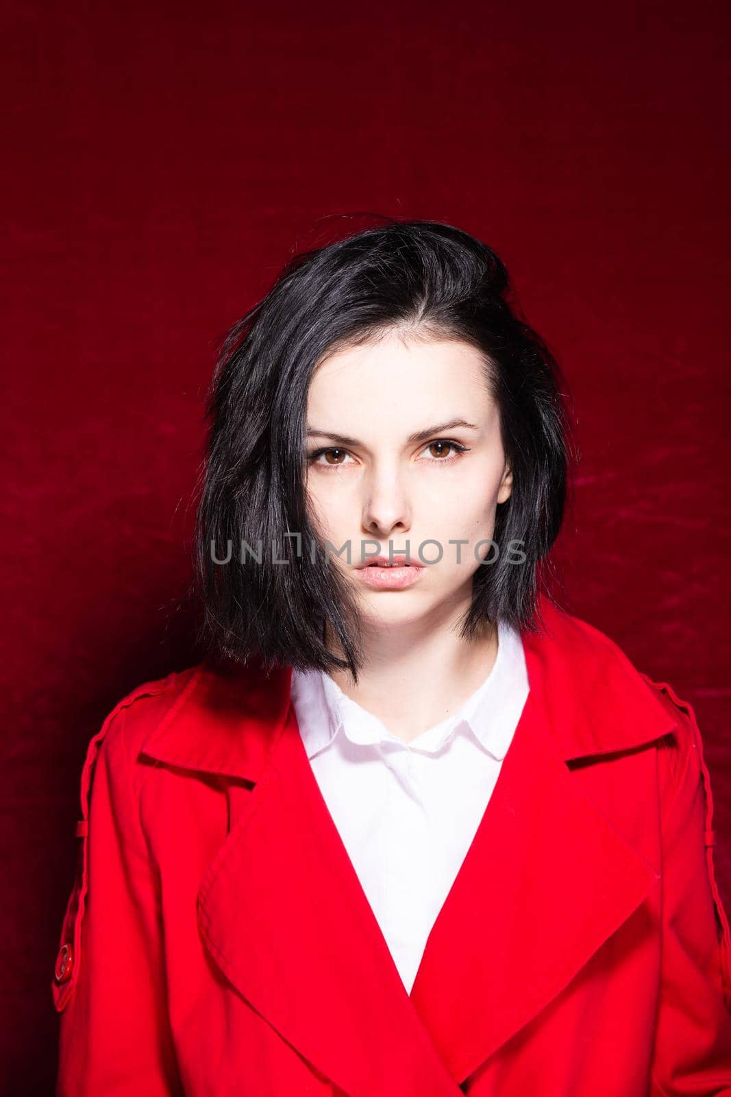brunette woman in a white shirt red trench on a red background by shilovskaya