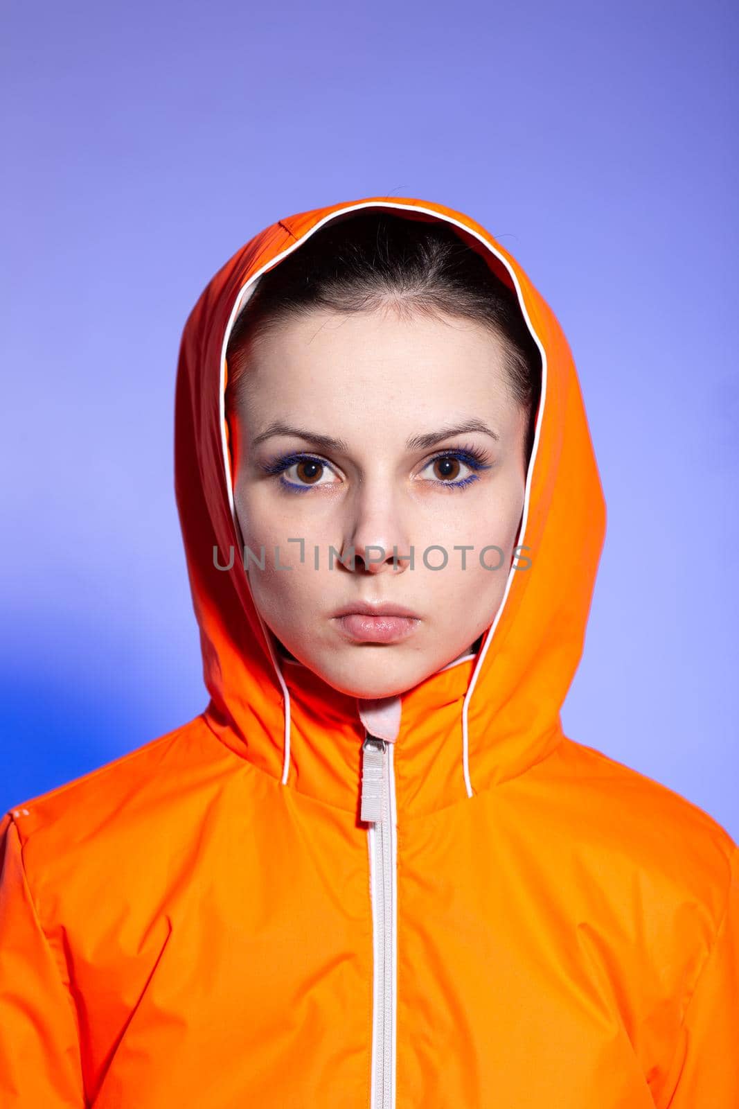 brunette woman in orange jacket, blue background. High quality photo