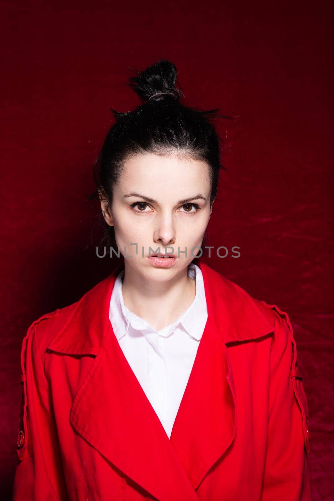 brunette woman in a white shirt red trench on a red background by shilovskaya