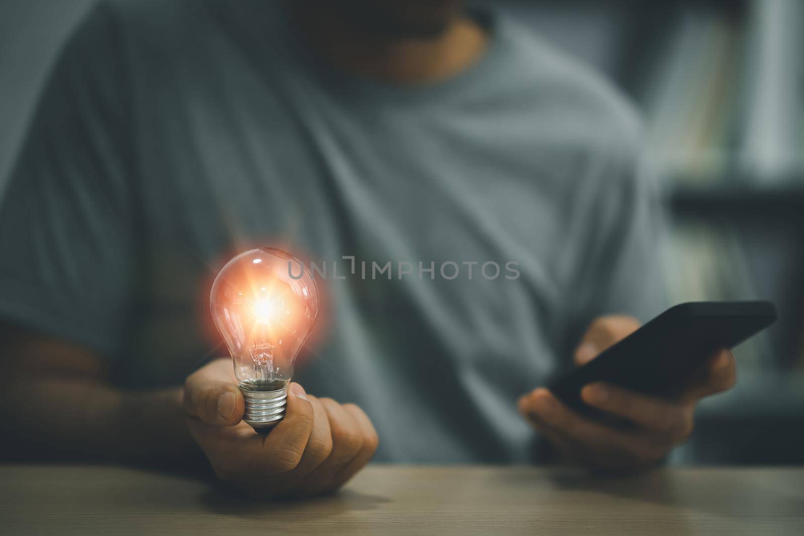 Businessman holding a bright light bulb and using mobile phone. Concept of Ideas for presenting new ideas Great inspiration and innovation new beginning. by Wmpix