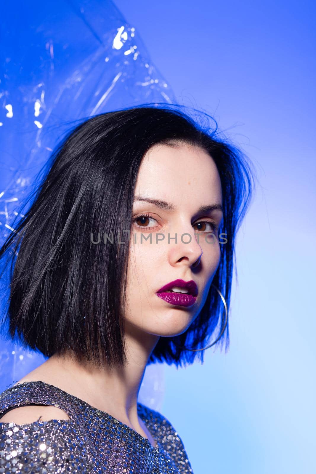 brunette woman with purple lips, blue background by shilovskaya