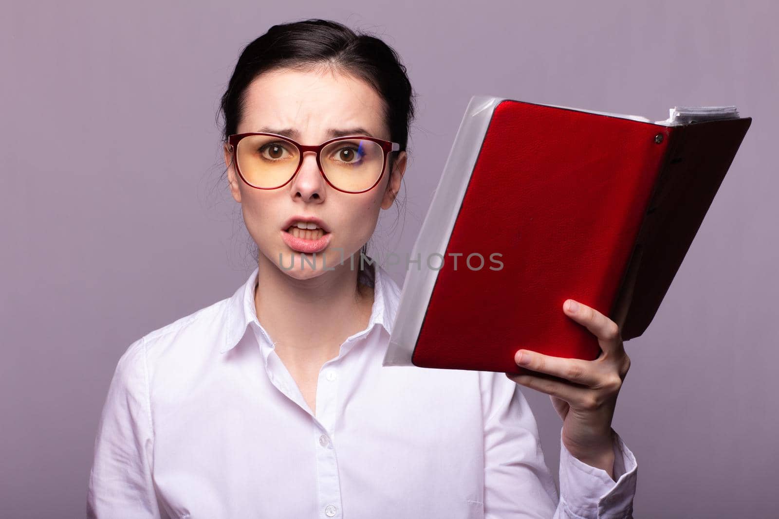 woman in a white shirt and glasses holds a red notebook in her hand. High quality photo