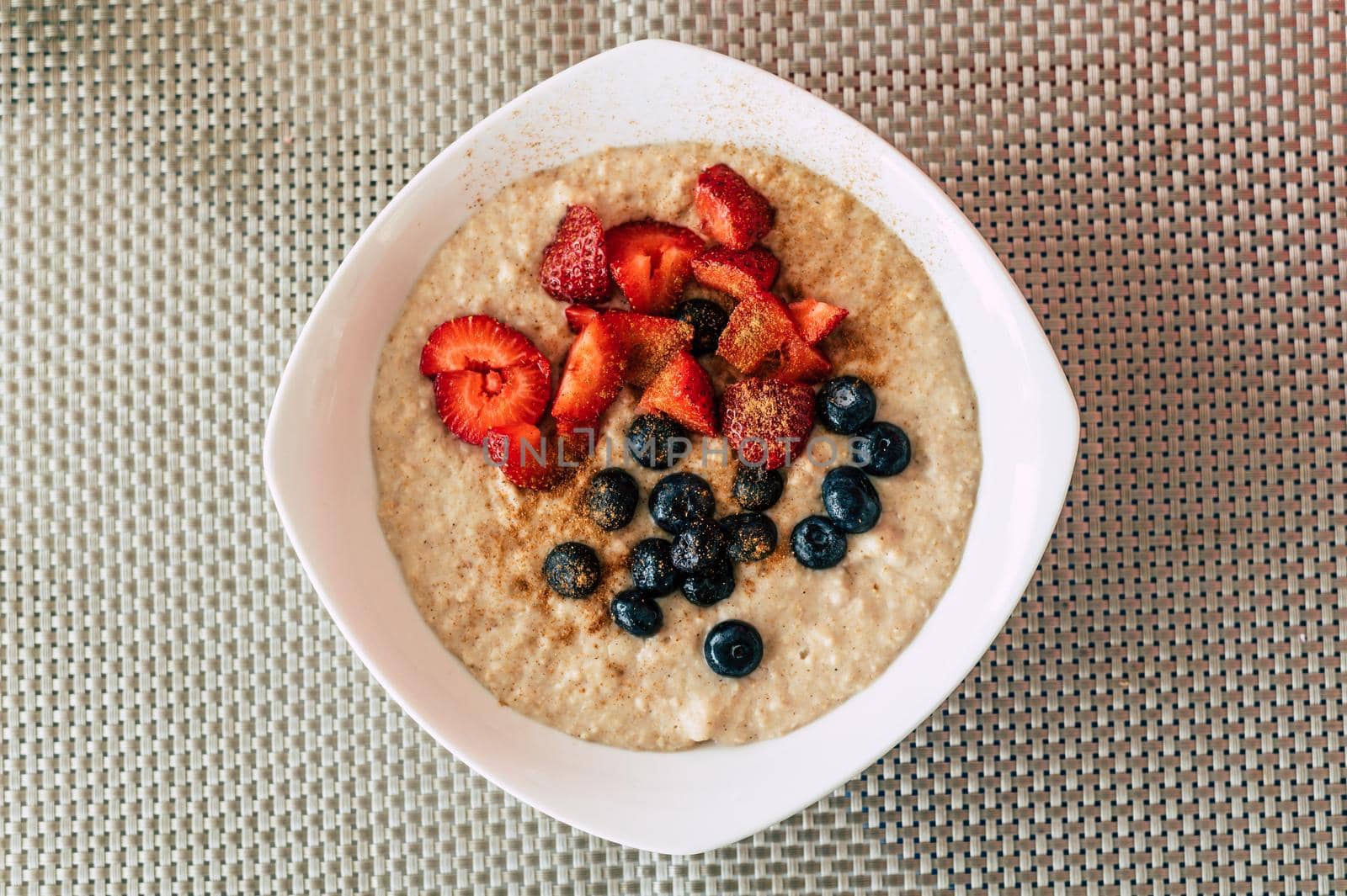 Homemade oatmeal with blueberries and strawberries in a bowl. Healthy breakfast. Top view