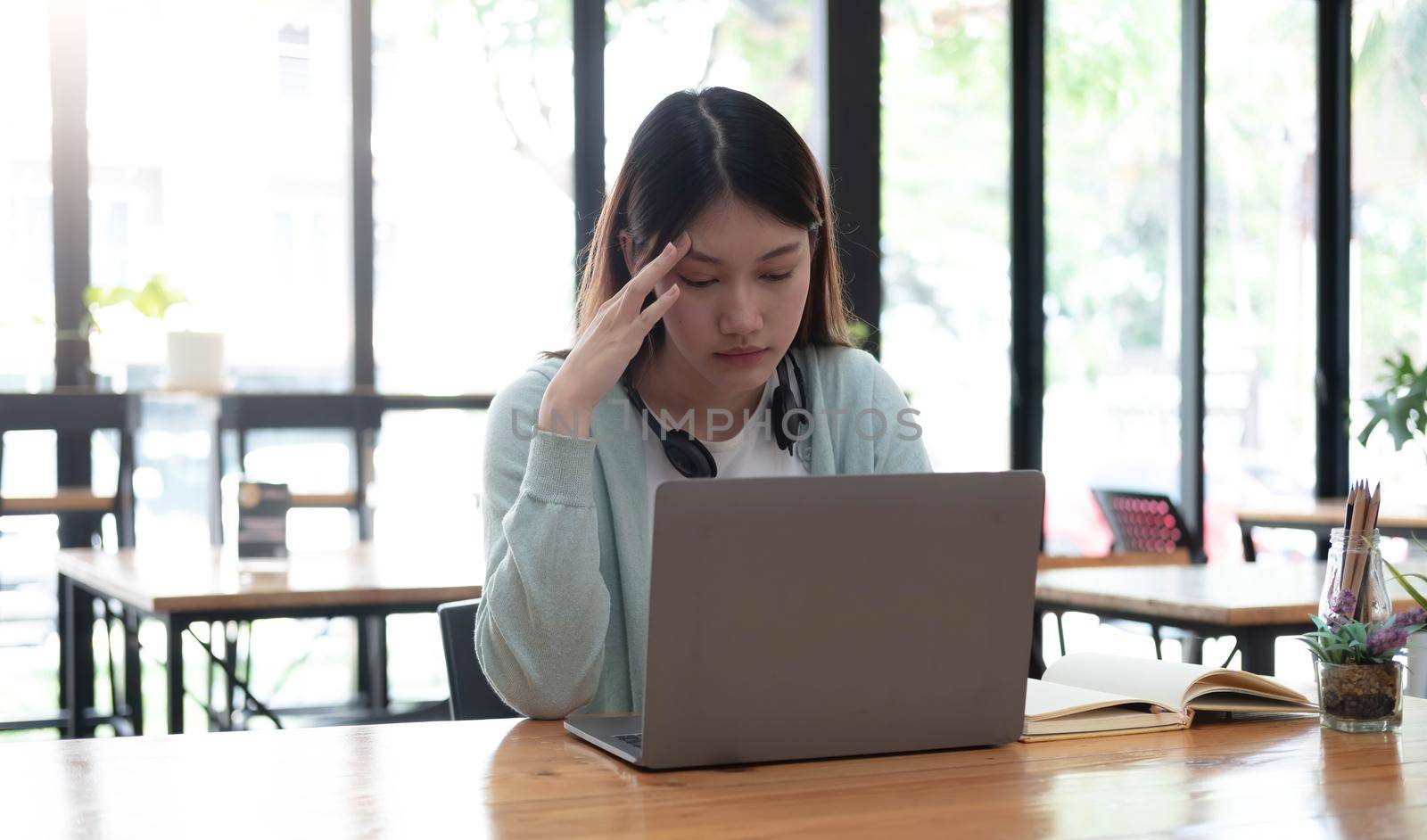 Serious focused Asian student using laptop in kitchen, looking at screen with attention and concentration, watching learning webinar, virtual training, video course, studying from home