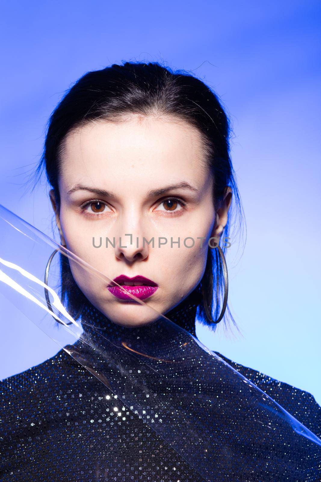 woman with purple lips in a black turtleneck with sequins on a blue background by shilovskaya
