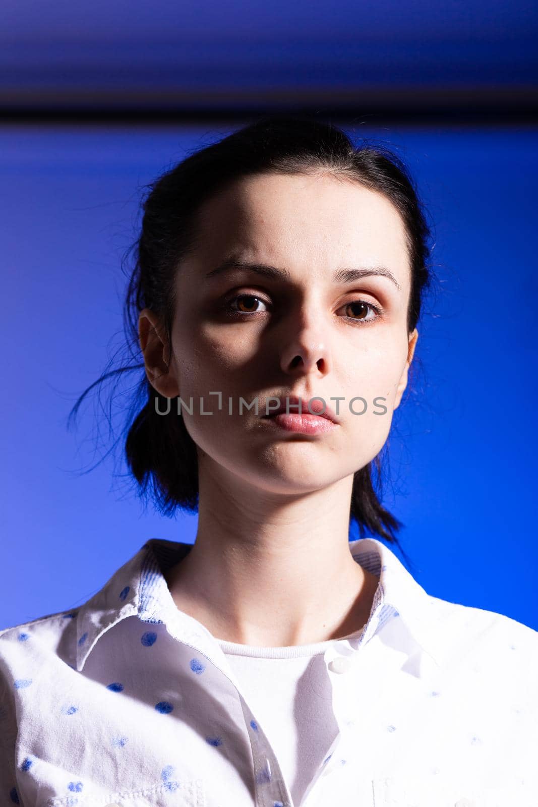 brunette woman in a white shirt with polka dots, on a blue background by shilovskaya