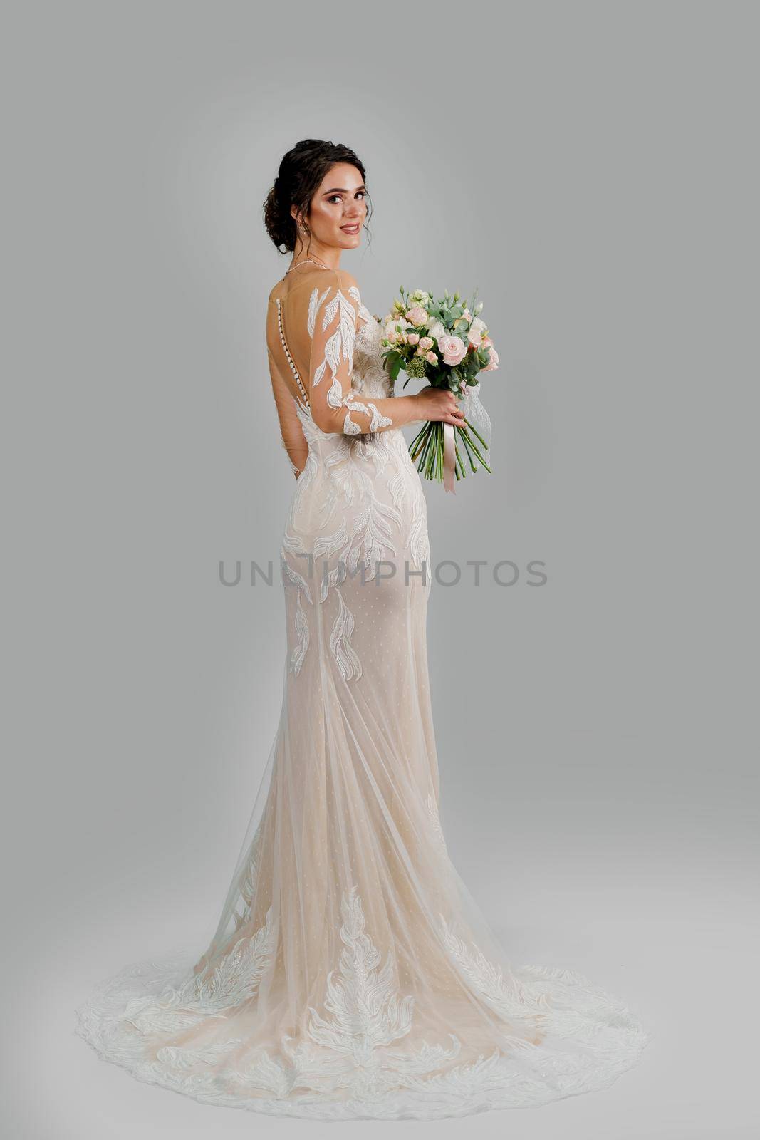 Girl in wedding dress on white blank background. Bride in white wedding dress with bouquet in studio