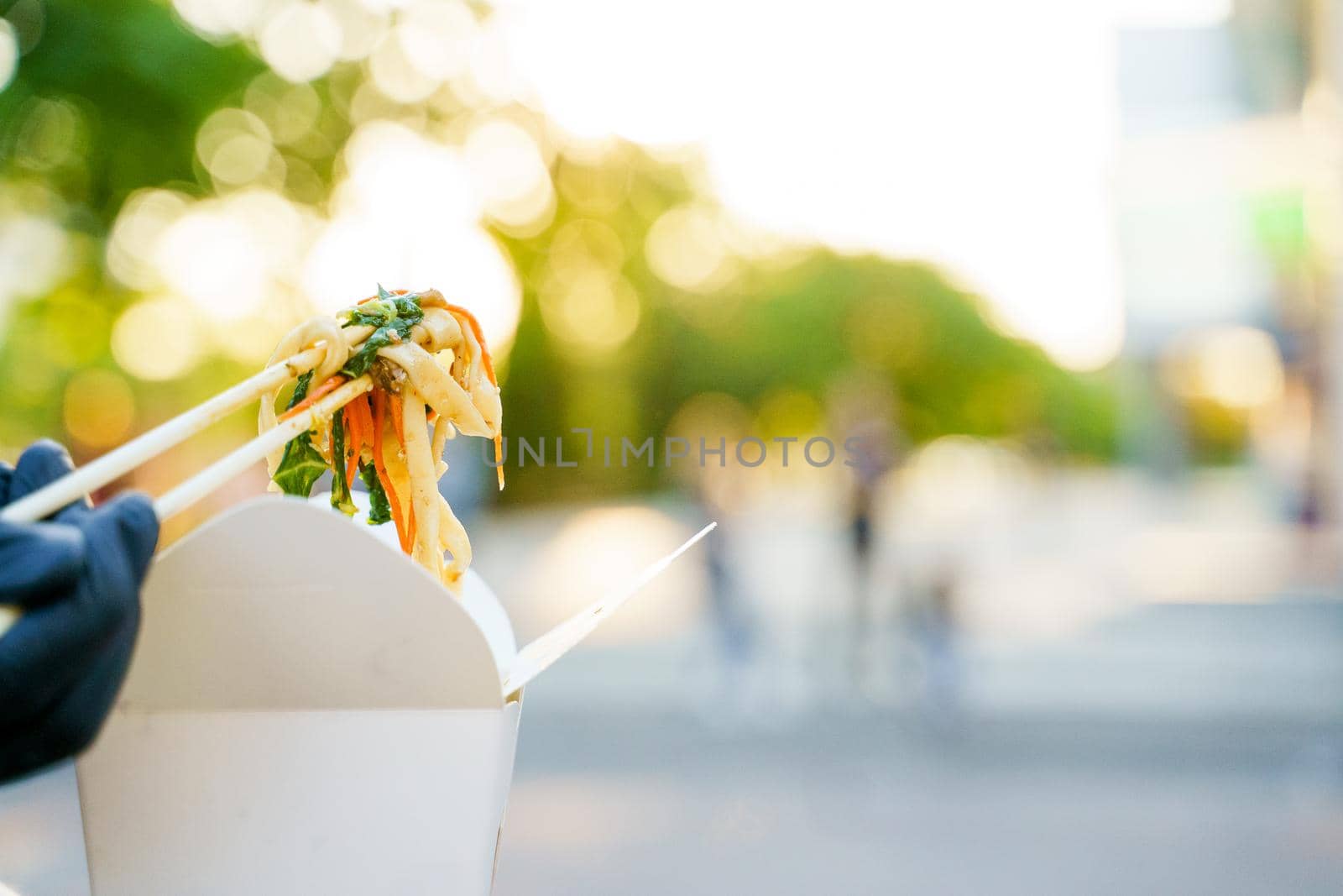 Close-up udon noddles on blurred background gets out of the white box. Stay at home and eat udon noodles with tempuru, shrimps, soy sauce by Rabizo