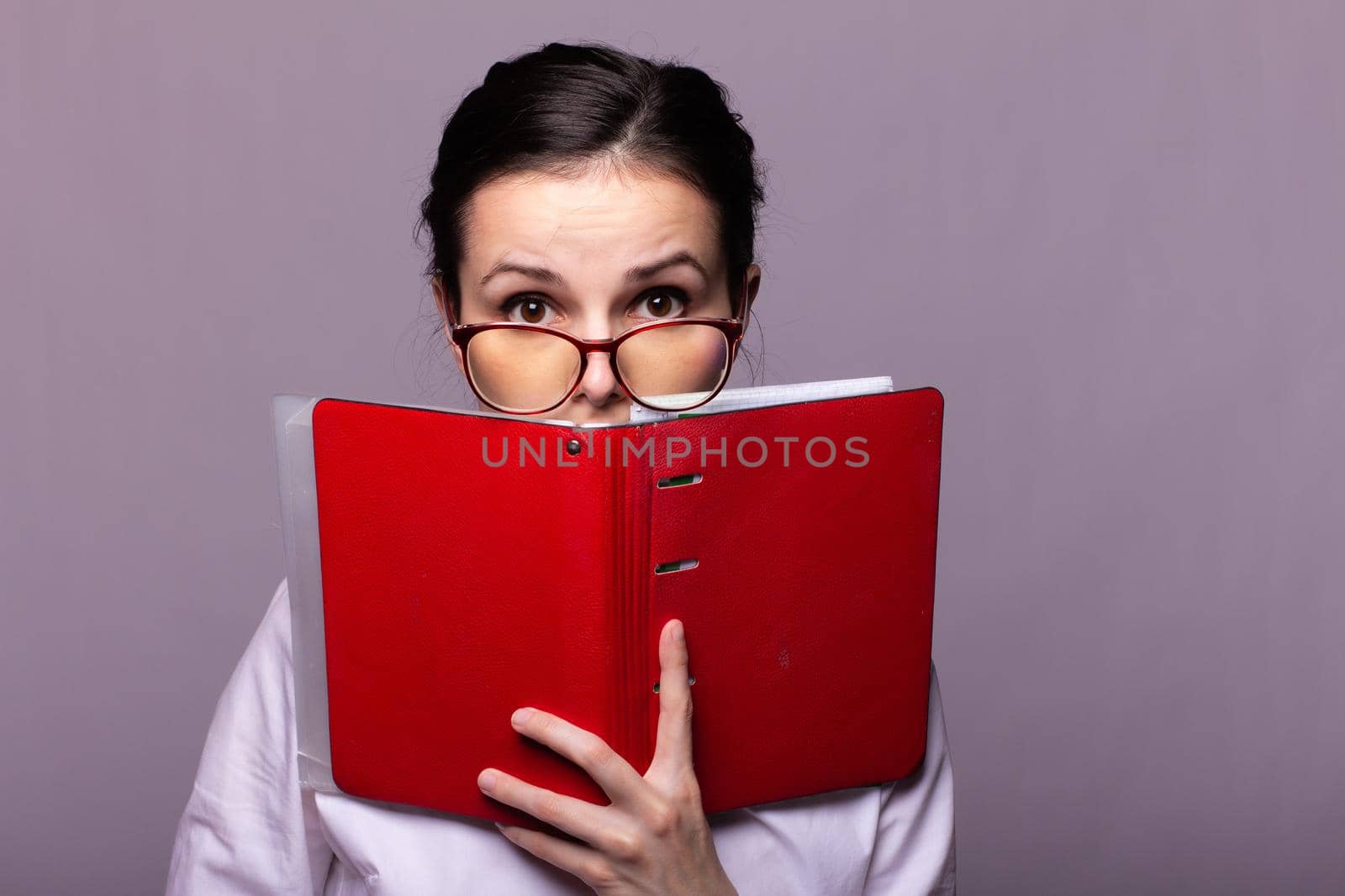 woman in a white shirt and glasses holds a red notebook in her hand by shilovskaya
