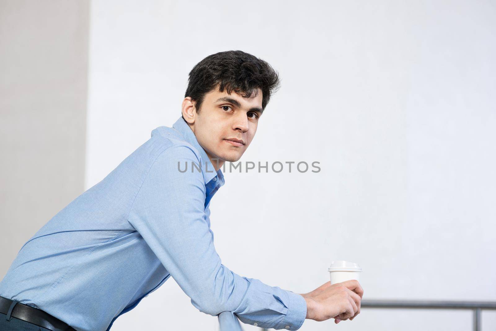 close-up portrait of a successful businessman. holds a paper cup of coffee and rests on a metal railing