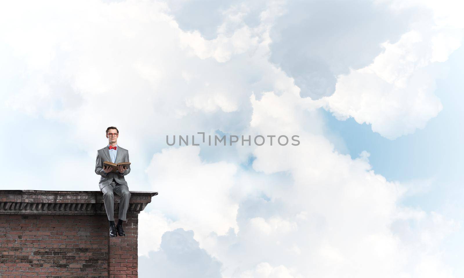 Funny man in red glasses and suit sitting on top and reading book