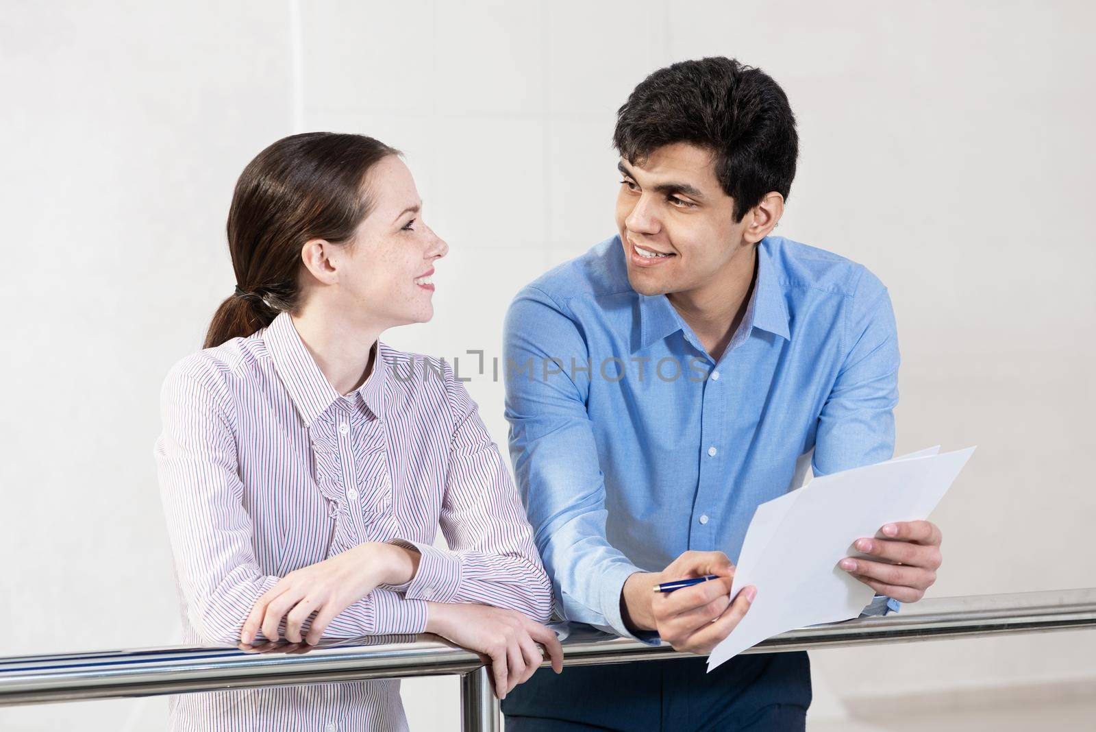 businessman and woman discussing document standing on balcony