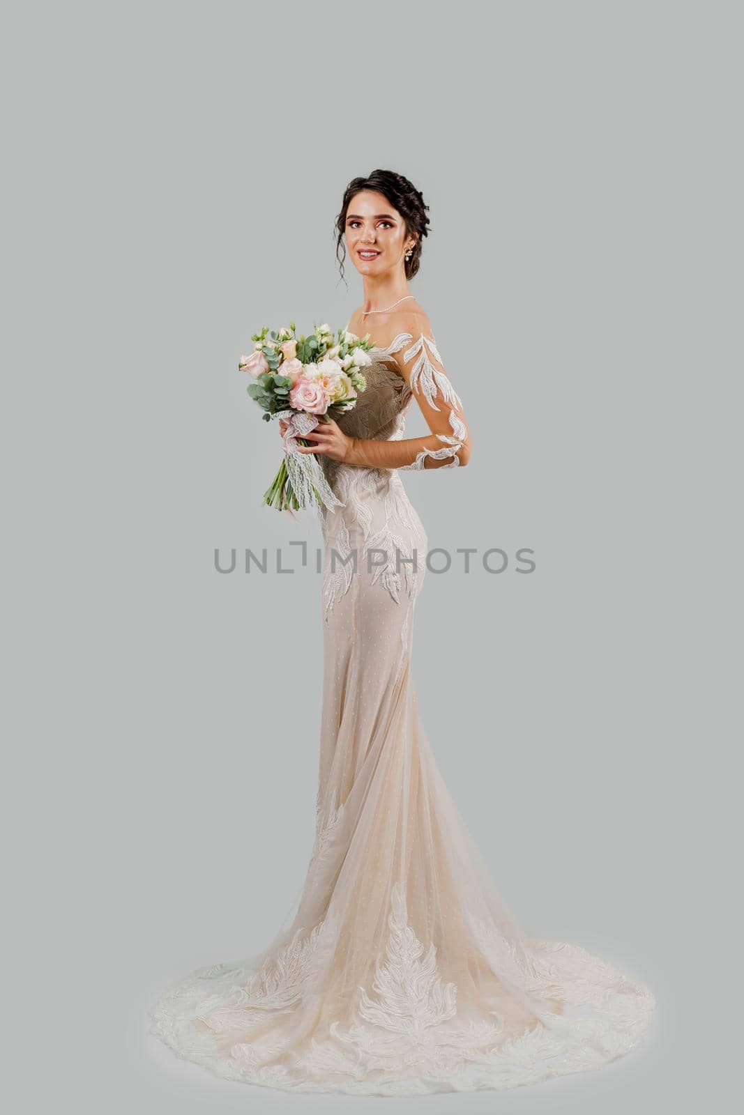 Girl in wedding dress on white blank background. Bride in white wedding dress with bouquet in studio