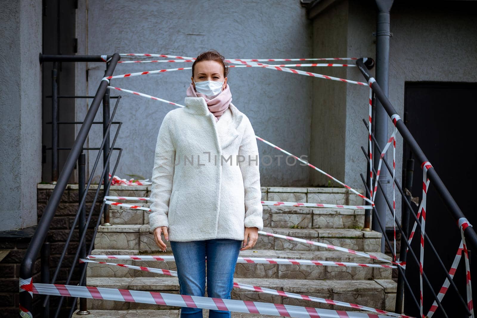 Photo of a girl in a mask. Standing on the street with danger warning tapes. isolated Covid-19 pandemic.