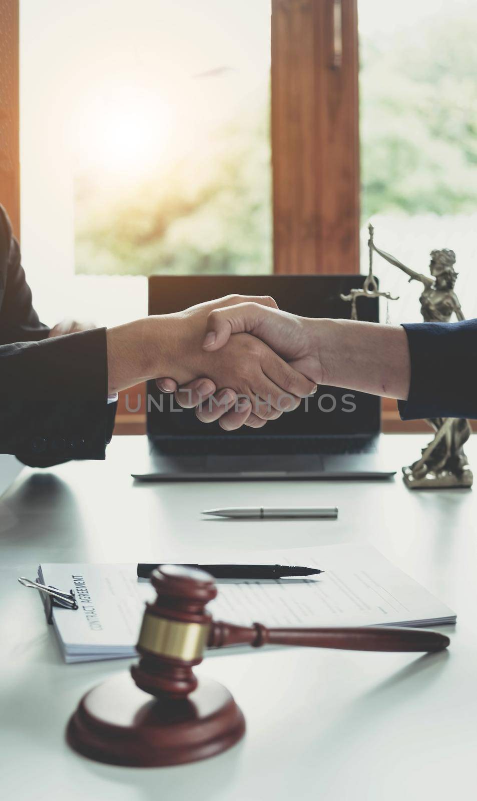 Businessman shaking hands to seal a deal with his partner lawyers or attorneys discussing a contract agreement. by wichayada