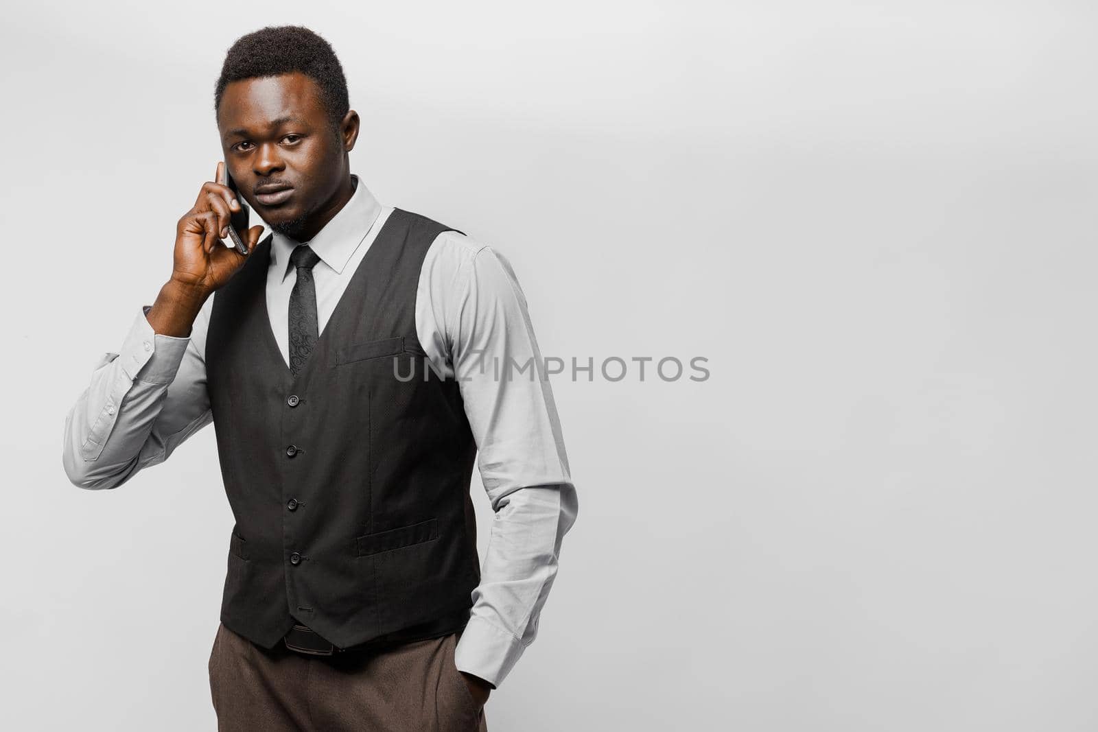 Handsome black task manager in IT company speaks with cusmomers by phone. African wears business style.