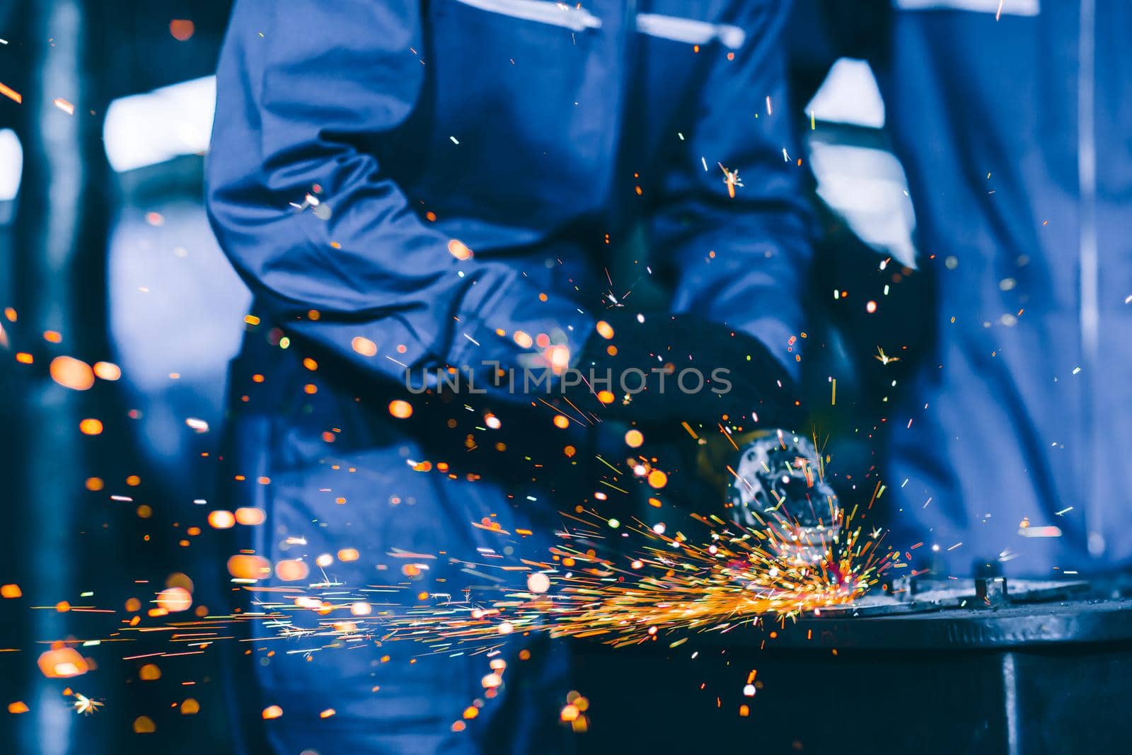 Closeup heavy steel worker using electric wheel grinding disc cuting metal plate in workplace danger fire light sparking from tool. by qualitystocks