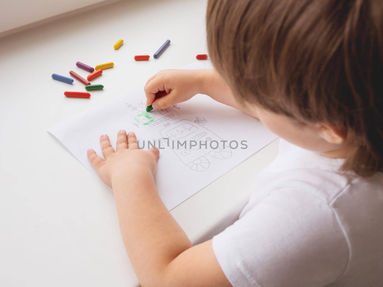 Toddler draws colorful robot. Kid uses wax crayons to paint it. Coloring pages to train fine motor skills. by aksenovko