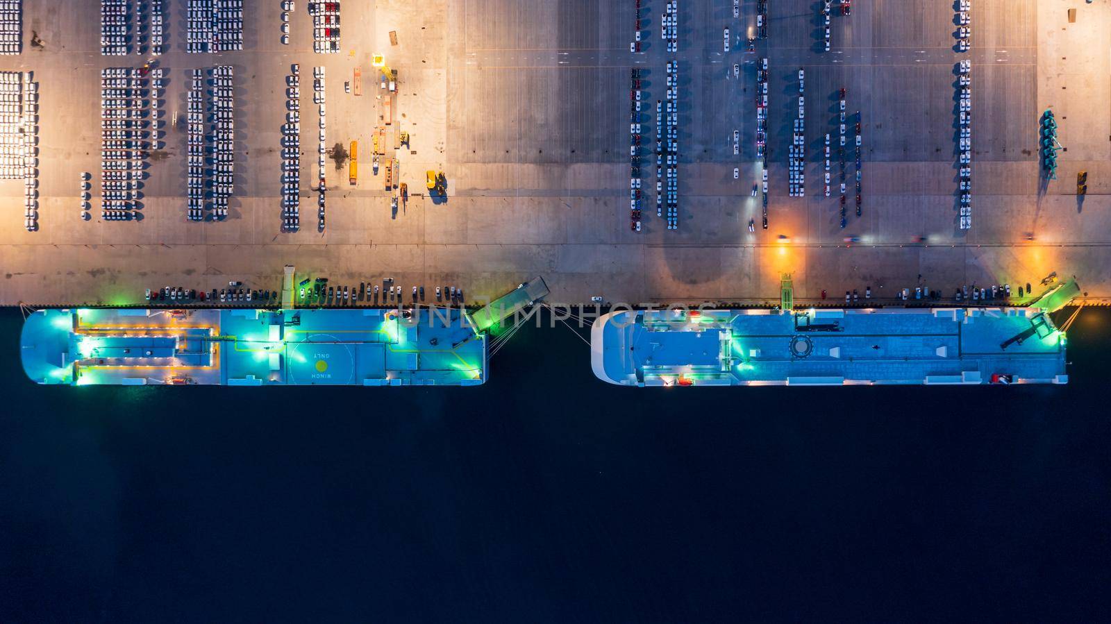 New car lined up in the port for import export around the world, Automobile and automotive roro carrier boat vessel terminal, Aerial view rows of new car at night waiting to be dispatch and shipped. by AvigatoR