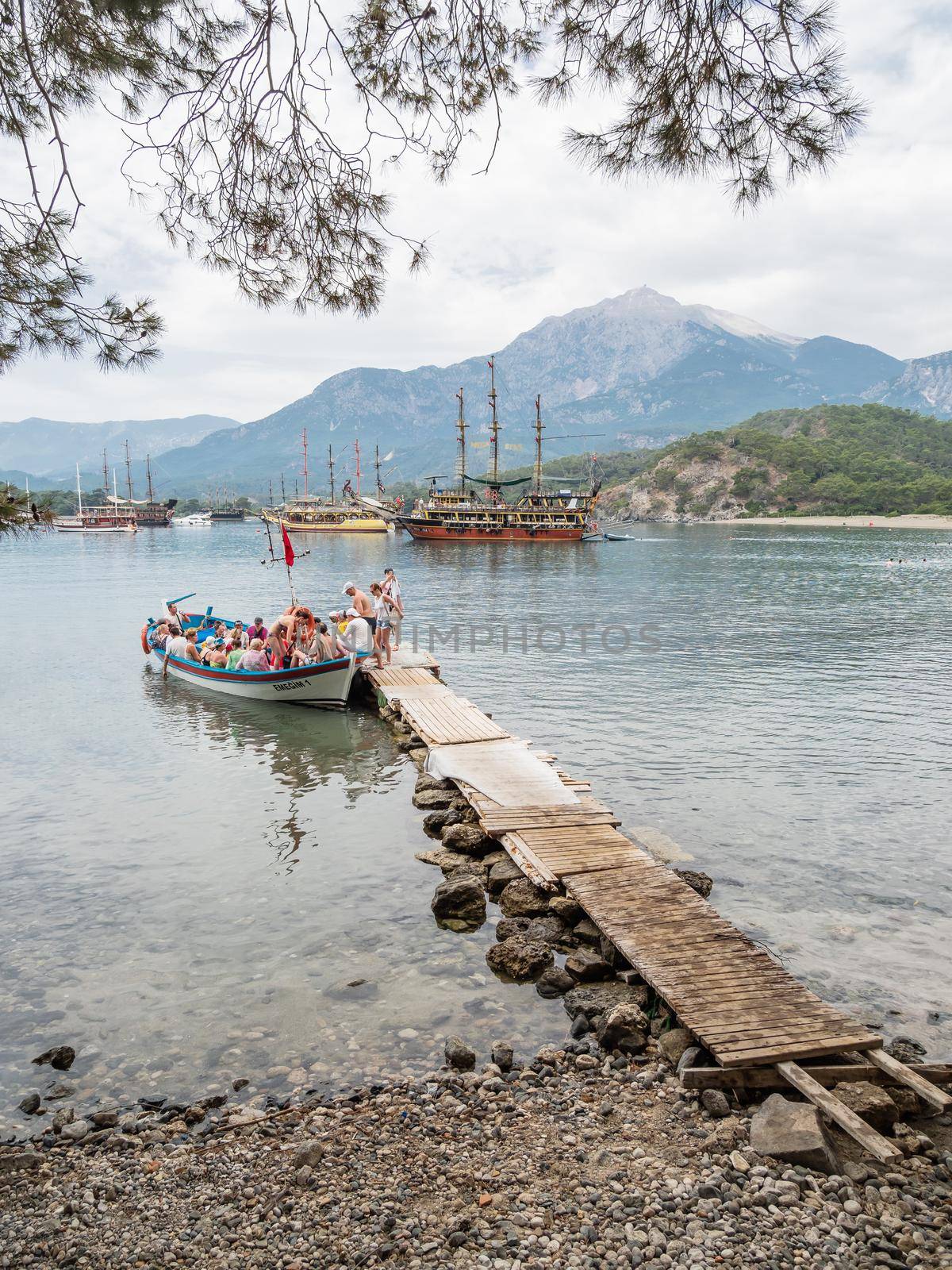 PHASELIS, TURKEY - May 19, 2018. Tourists get into the boat after excursion. Touristic yachts and boats in harbour of ancient ruins of Phaselis city. by aksenovko