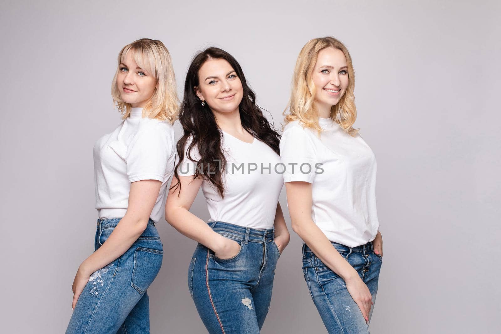 Three beautiful women in white shirts and jeans posing by StudioLucky