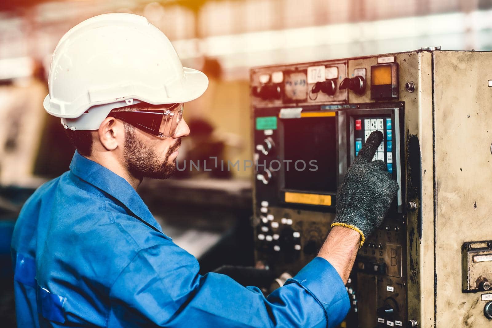 Hispanic latin worker working with machine in heavy industry factory, CNC programming. by qualitystocks