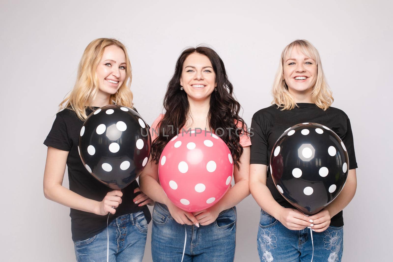 Three female friends celebrating a party event having fun and smiling with balloons
