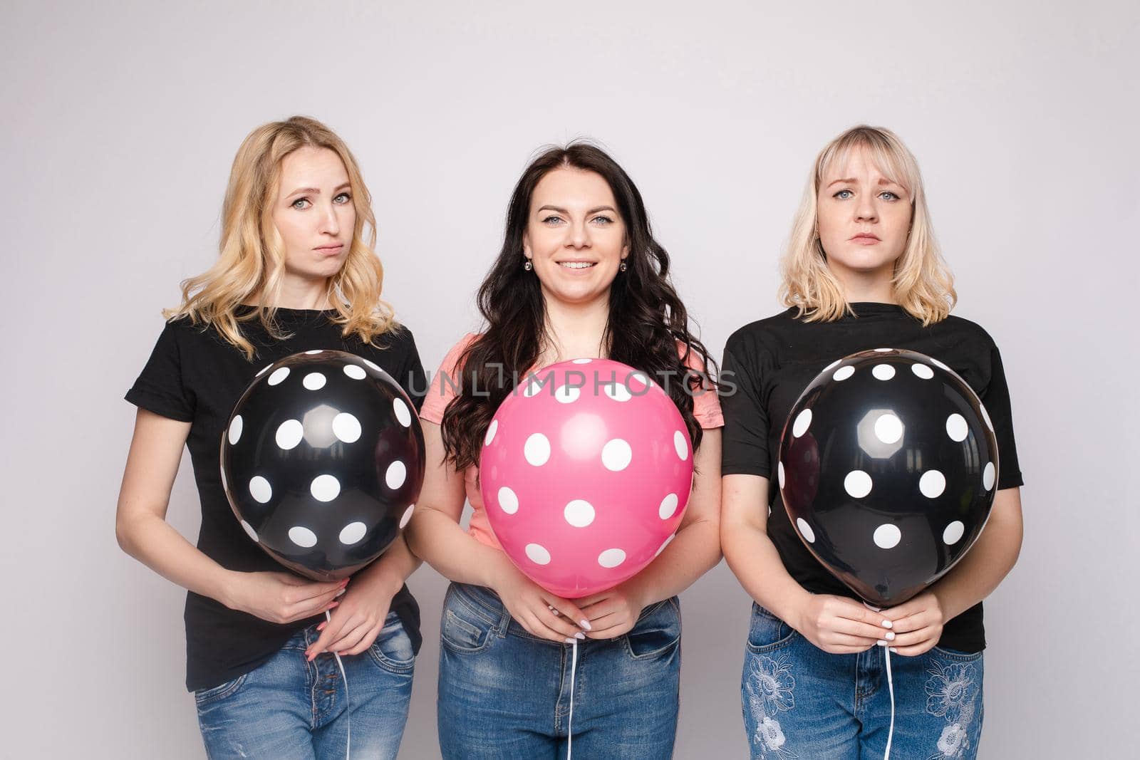 Three female friends celebrating a party event having fun and smiling with balloons