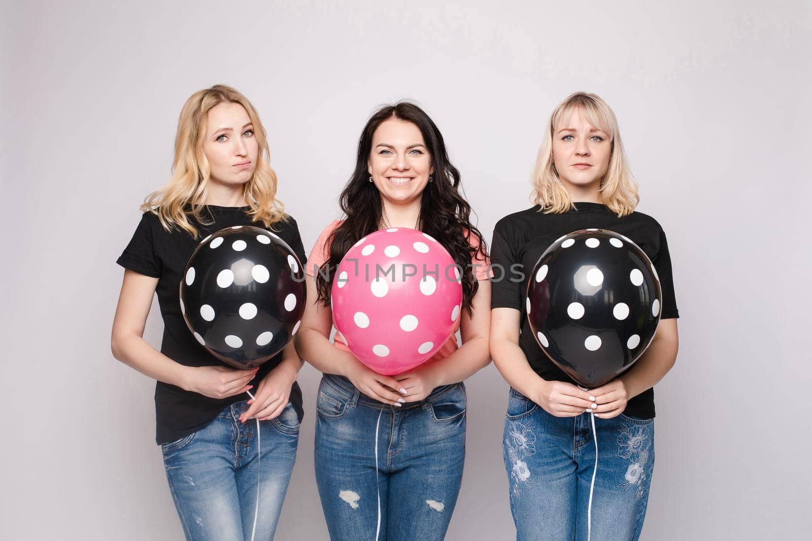 Three female friends celebrating a party event having fun and smiling with balloons