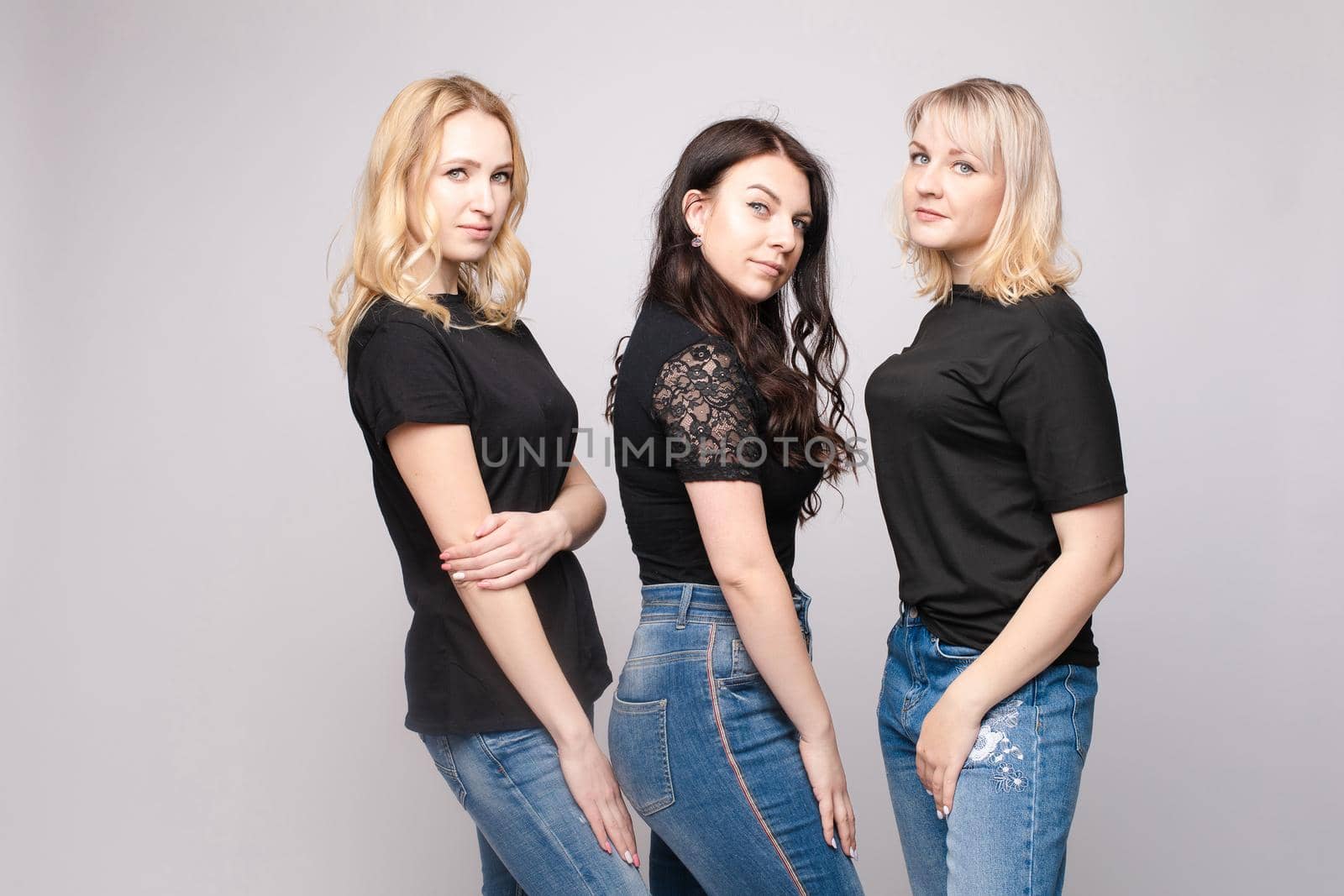 Group of smiling young friend woman hugging posing looking at camera isolated at white studio background. Adorable happy female enjoying friendship having positive emotion medium long shot