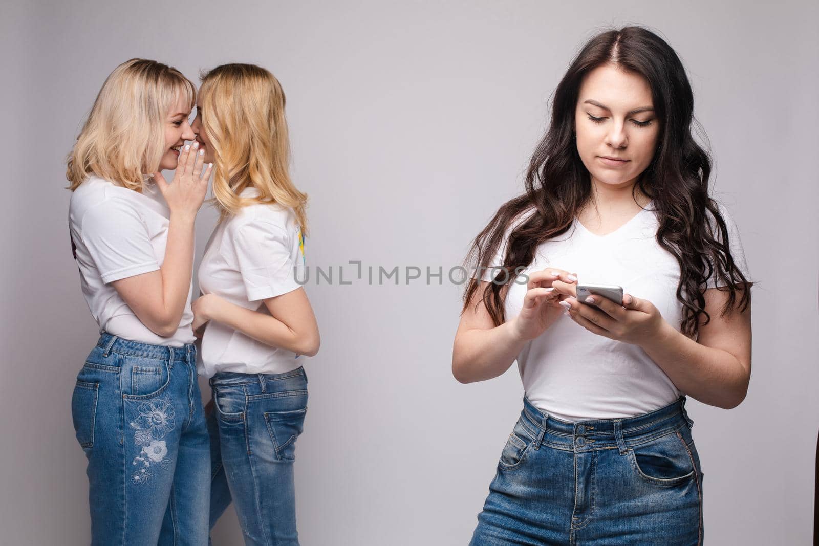 Offended brunette and two blondes gossiping behind by StudioLucky