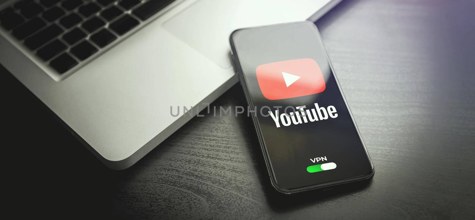 MOSCOW, RUSSIA - MAY 04, 2022: iphone lying on a wooden table, on the screen Youtube video application logo, which open only after turning on the vpn connection. Government censorship concept by bestforbest