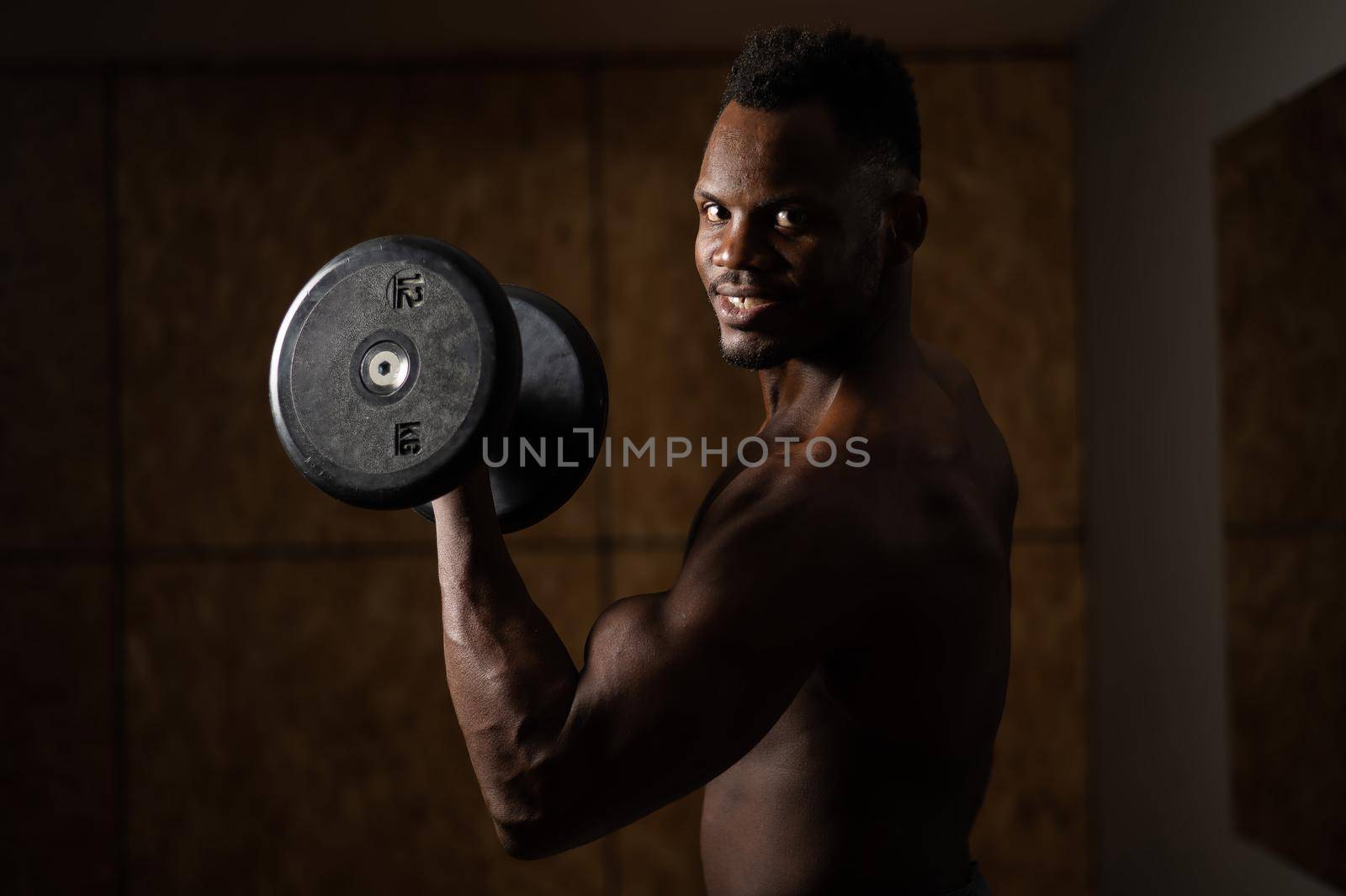 Attractive african american man smiling and doing exercise with dumbbells